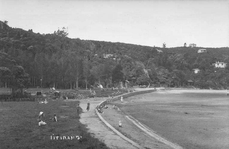 Looking north east along Titirangi beach showing baches in bush clad hills behind.1934. Sir George Grey Special Collections, Auckland Libraries.