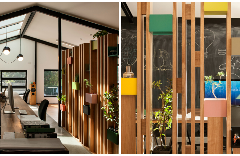 This slatted wooden room divider in the offices of Social Fabric allows light to penetrate into the back room and doubles as a plant holder and a display wall.